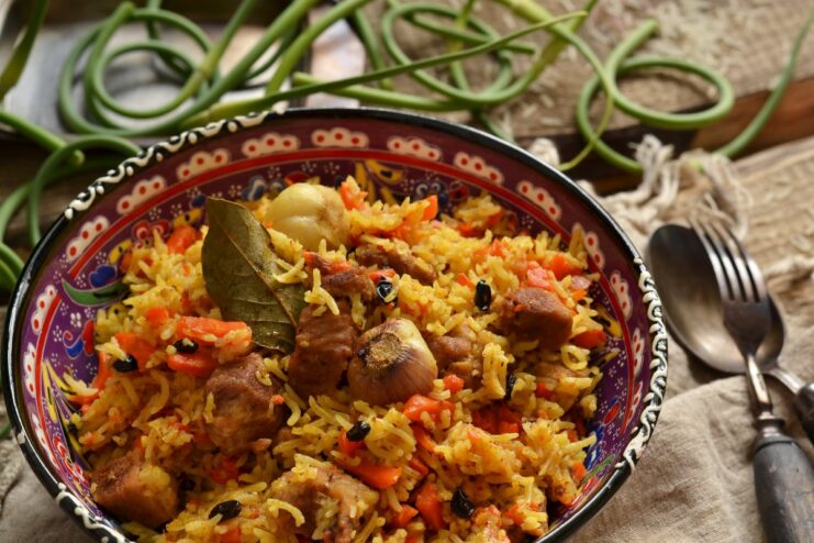 A large platter of delicious pork plov cooked in a Dutch oven, ready to be served.