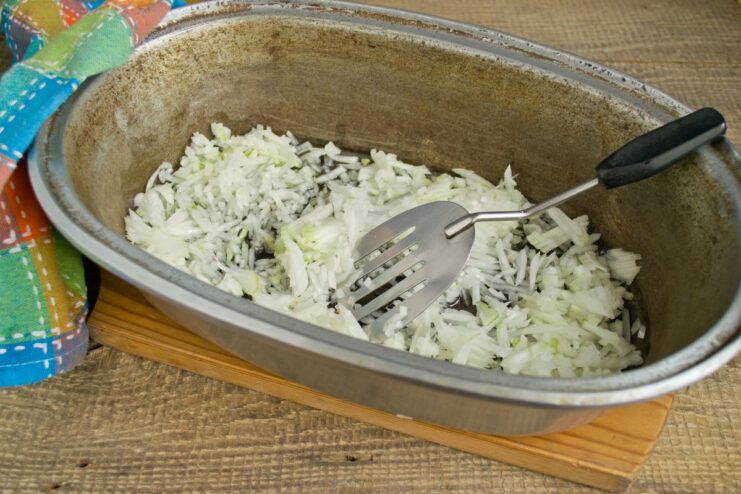 The first step to building flavor: sautéing onions until soft and translucent. Finely chopped onions being sautéed until translucent in a cast-iron Dutch oven.