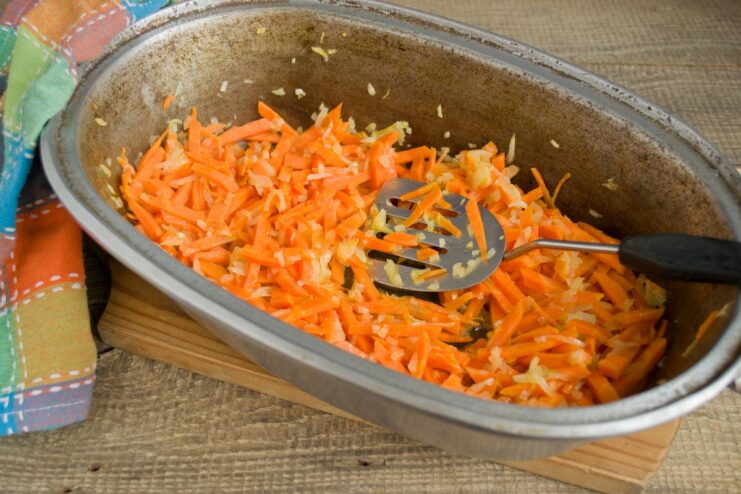 Adding carrots to the onions for a sweet and savory base. Sliced carrots being added to the sautéed onions in the Dutch oven.