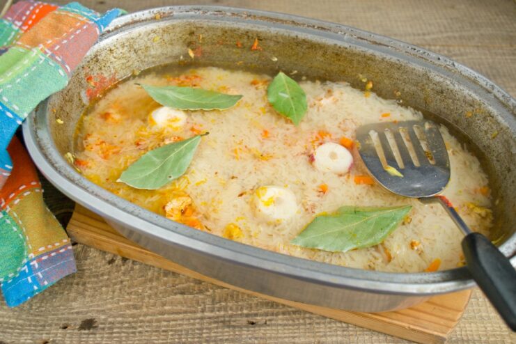 Carefully pouring in water to cook the rice perfectly. Water being carefully poured into the Dutch oven over the rice and other ingredients.