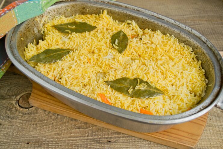 Letting the plov rest is a crucial step for perfectly fluffy rice. The covered Dutch oven simmering on the stove, with a towel over the lid.