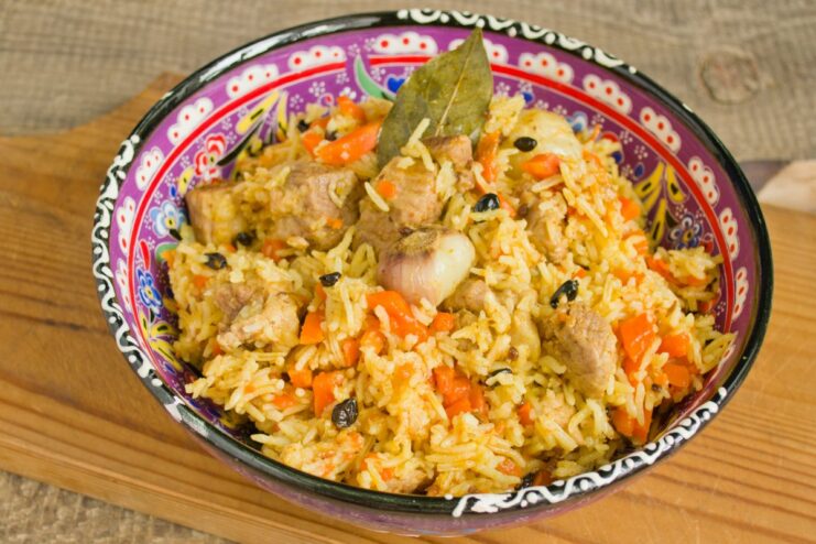 The finished pork plov, perfectly cooked and ready to be enjoyed. A spoonful of the finished pork plov, showing fluffy rice, tender meat, and carrots.