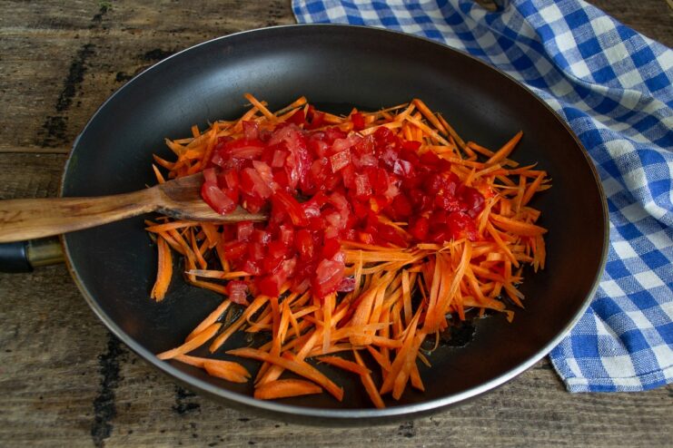Diced fresh tomatoes being added to the pan with other vegetables.