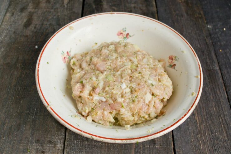 Seasoning and Mixing the Chicken Mince for Cutlets Hands mixing seasoned minced chicken, onion, bread, and fennel in a bowl.