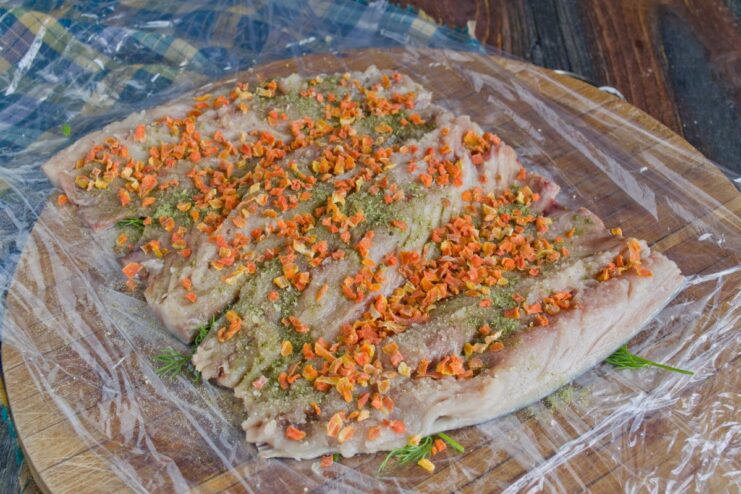 Adding a Layer of Dried Carrot for Flavor and Color Dried carrot flakes being sprinkled over the seasoned mackerel fillets.