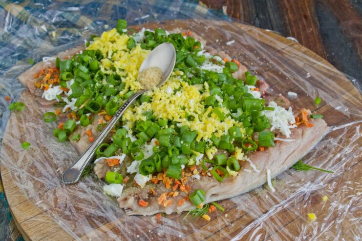 Creating the Colorful Center with Grated Egg Yolk A line of grated egg yolk placed in the center of the mackerel filling, ready for rolling.