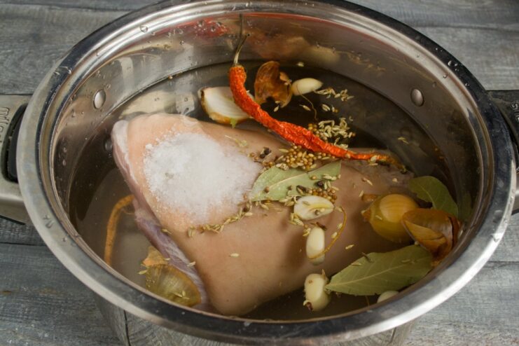 Step 5: Seasoning the Broth with Salt and Spices Adding salt, fennel seeds, and coriander seeds to the pot with the pork knuckle.