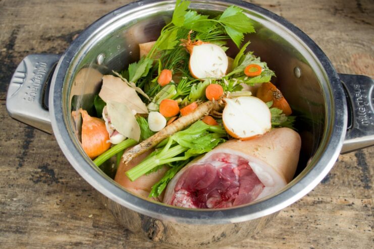 Adding Aromatic Vegetables and Spices for a Rich Flavor Pork knuckles in a pot with added carrots, onions, celery, and garlic.