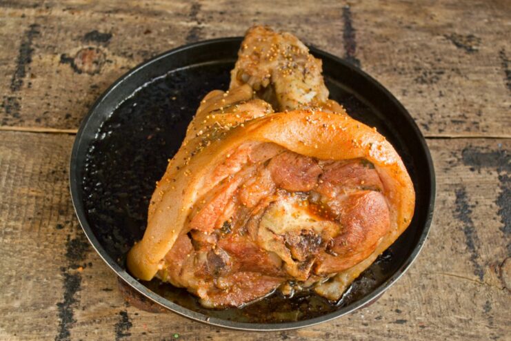 Final Step: Roasting to Get That Perfect Crispy Crust A golden-brown pork knuckle with crispy skin on a baking sheet after being roasted.