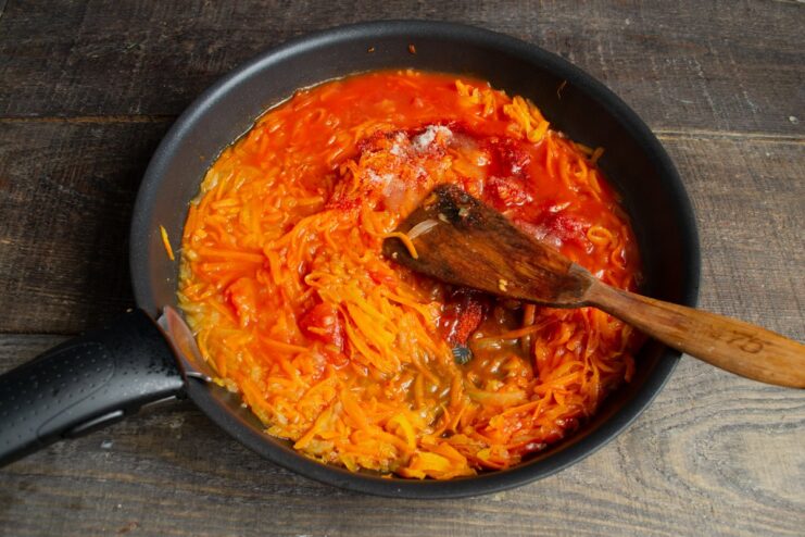 Simmering the vegetable marinade with tomatoes and spices Carrot and onion marinade simmering in a skillet with canned tomatoes and spices.