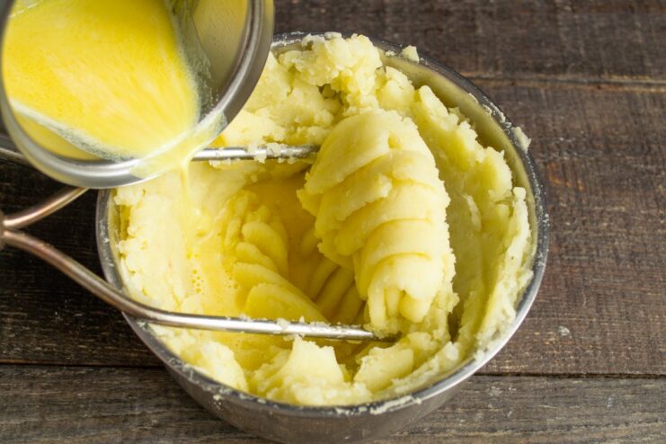 Step-by-step guide to making creamy mashed potatoes Mashing cooked potatoes in a pot to prepare mashed potatoes.