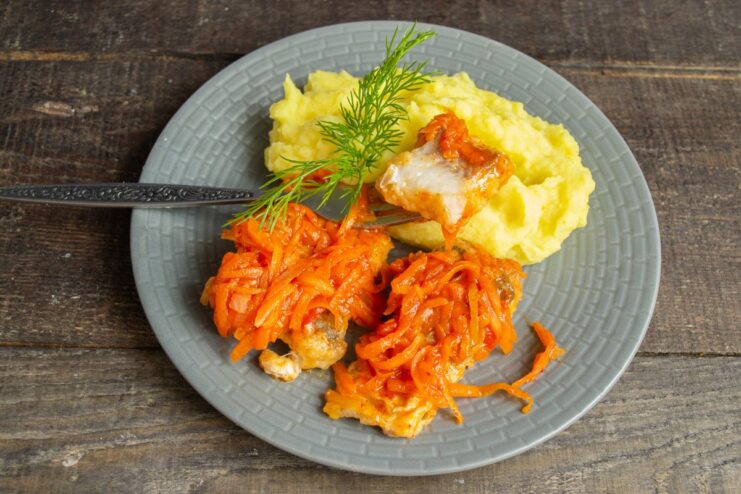 The final dish: Fish in Carrot and Onion Marinade with Mashed Potatoes The finished dish of fish in marinade with mashed potatoes served on a plate.