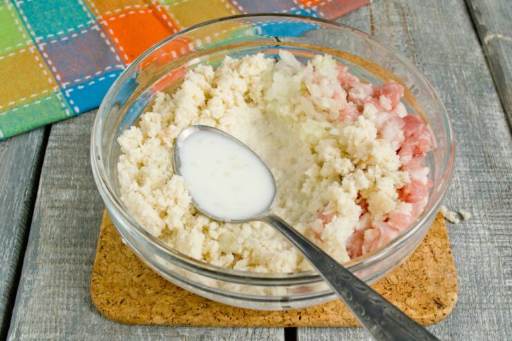 Seasoning the Pork Mixture with Milk and Salt Milk and salt being added to the ground pork mixture in a bowl.