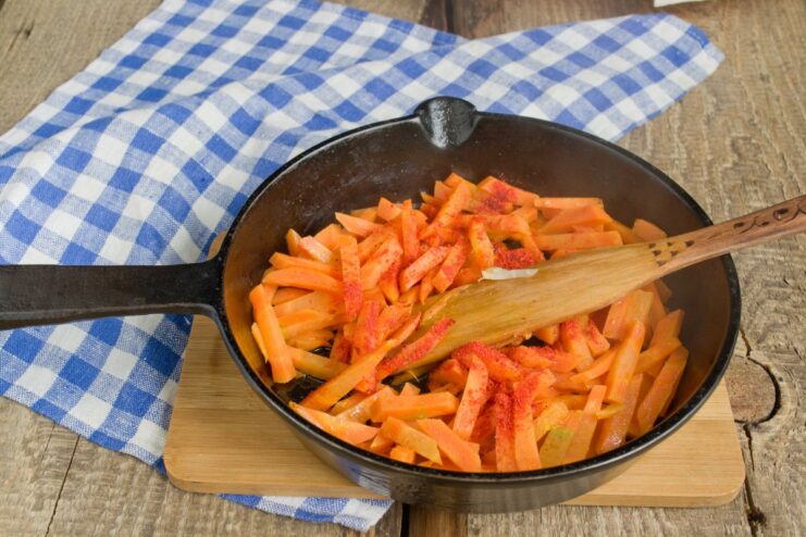 Sautéing carrots for the plov layer Julienned carrots being sautéed in the same pan used for the meat.