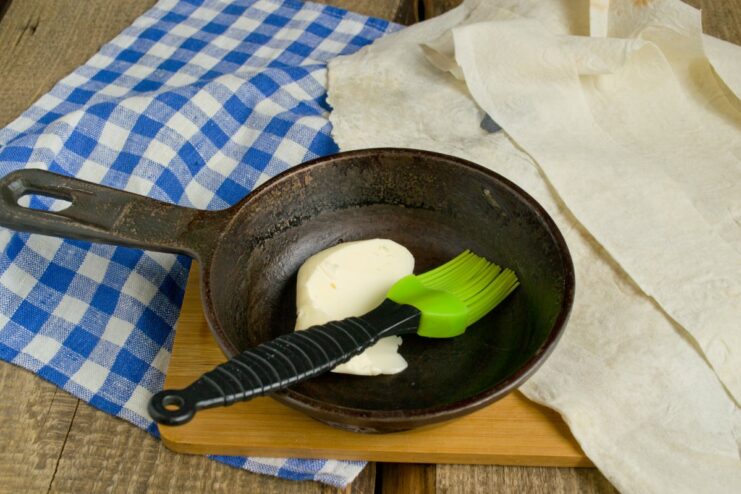 Preparing lavash strips and melted butter for lining the pot Strips of lavash bread next to a small bowl of melted butter.