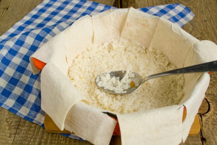 Adding the first layer of cooked rice over the lavash The first layer of cooked rice spread over the lavash lining in a pot.