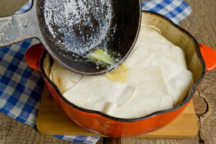 Sealing the Shah Plov by folding the lavash strips over the filling Lavash strips being folded over the filling to enclose the plov.
