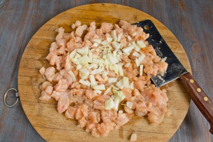 Adding Finely Chopped Onion to the Chicken Mixture Chopped chicken and finely diced onion mixed together in a bowl.