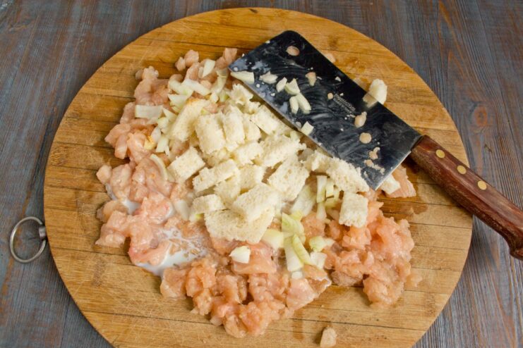 Soaking Stale Bread in Cream to Add Moisture to the Schnitzel Cubes of stale white bread being soaked in heavy cream on a cutting board.