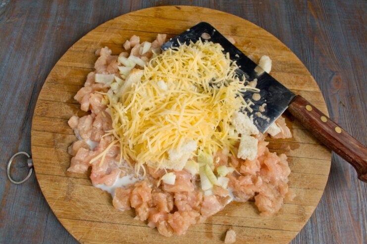 Grating Parmesan Cheese for a Rich, Savory Flavor A hand grating a block of Parmesan cheese over the chopped chicken mixture.