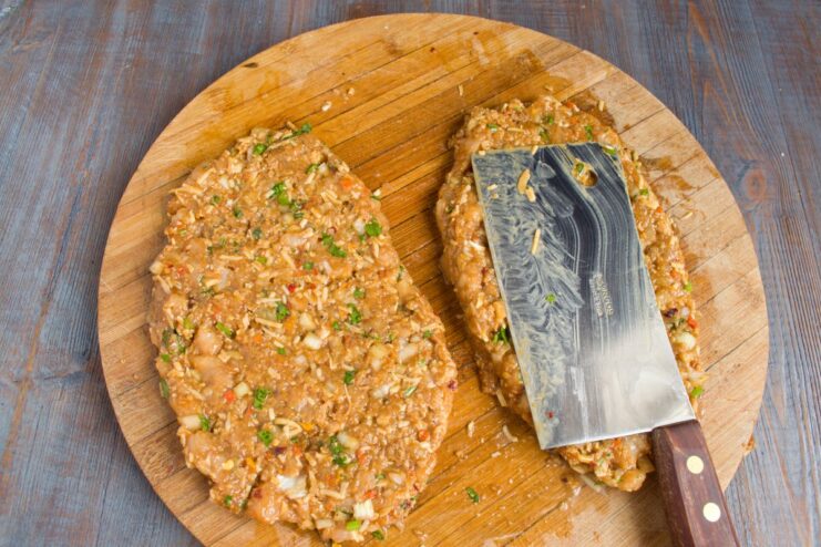 Dividing and Shaping the Chopped Chicken Mixture into Schnitzels The prepared chopped chicken mixture divided into two portions on a cutting board.