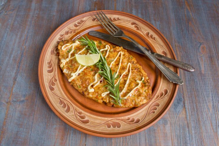 The Perfectly Baked Chopped Chicken Schnitzel is Ready to Serve! A finished baked chopped chicken schnitzel on a plate, garnished with herbs and ready to eat.