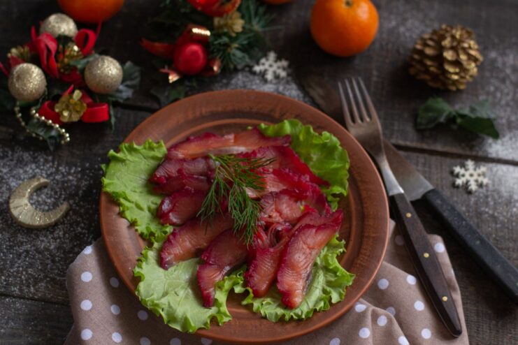 A plate of thinly sliced beetroot gravlax, a Scandinavian cured salmon appetizer, ready to be served.