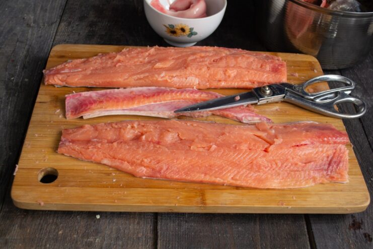 Preparing the Salmon Fillet: Removing Bones and Trimming Using tweezers to remove small pin bones from a fresh salmon fillet.