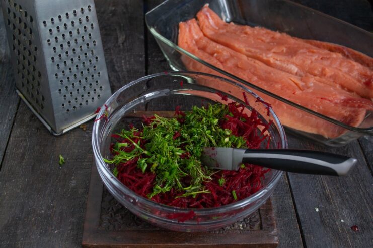Adding Fresh Dill to the Beetroot Cure Finely chopped fresh dill being added to a bowl of grated beetroot.