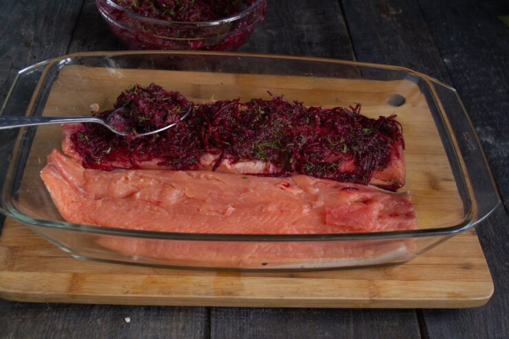 Applying the Beetroot Cure to the Salmon Fillet A salmon fillet being covered evenly with the vibrant red beetroot and dill cure.