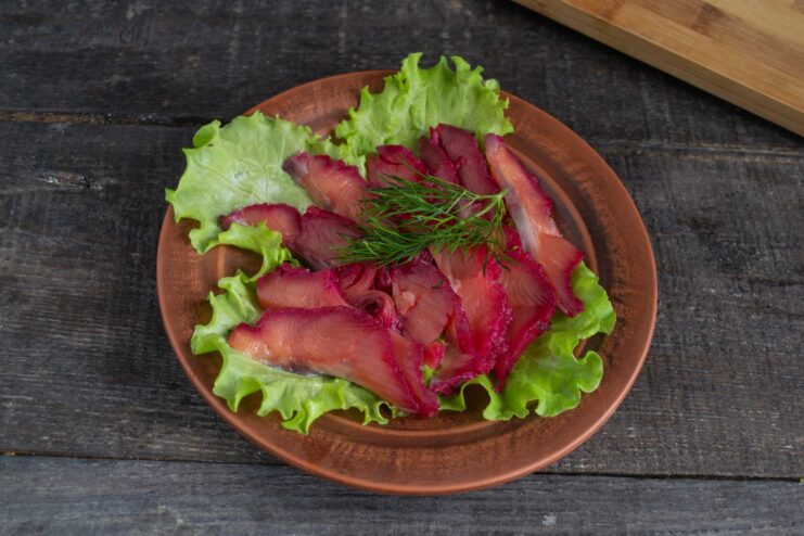 Serving the Elegant Beetroot Gravlax Appetizer Beautifully sliced beetroot gravlax arranged on a bed of fresh lettuce leaves, ready to serve.