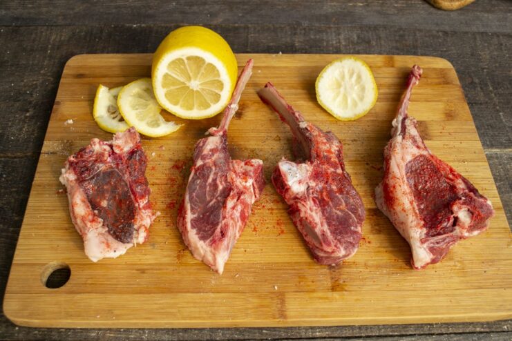 Marinating the lamb chops with fresh lemon juice Squeezing lemon juice over seasoned lamb chops.