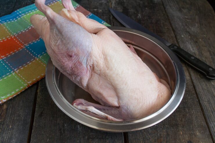 Preparing the Duck for Roasting A raw whole duck being prepared for marinating on a cutting board.