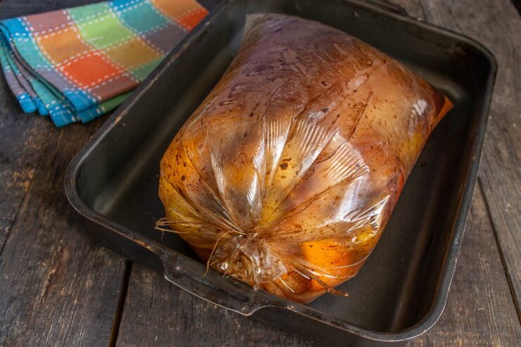 Roasting the Duck Until Golden Brown The duck roasting in the oven inside a bag, turning golden brown.