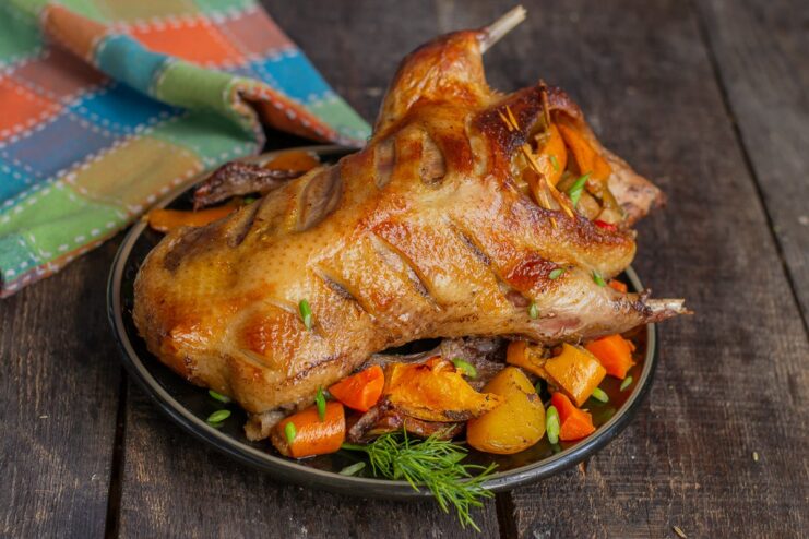 Serving the Roasted Duck with Pan Sauce The finished roasted duck with oranges served on a platter with a side of rich pan sauce.
