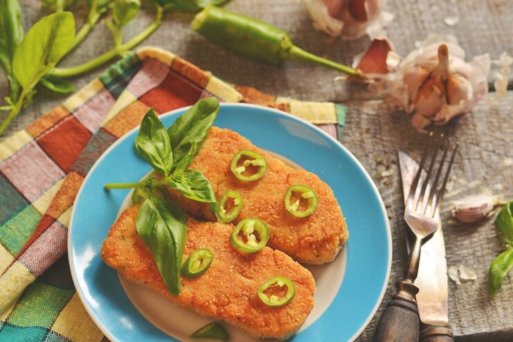 A plate of juicy chicken cutlets with crispy breading, garnished with herbs.