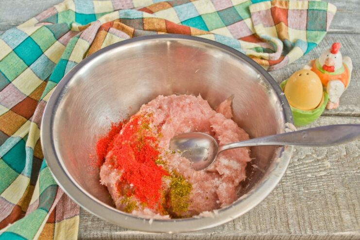 The process of kneading ground chicken with spices for extra tender cutlets A bowl of seasoned ground chicken being mixed by hand.