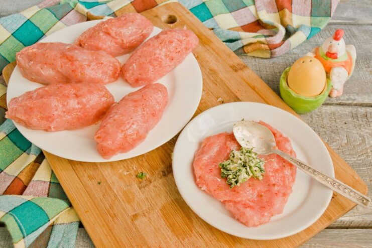 How to shape chicken cutlets with a butter filling inside Hands forming a ground chicken patty with a dollop of herb butter filling in the center.