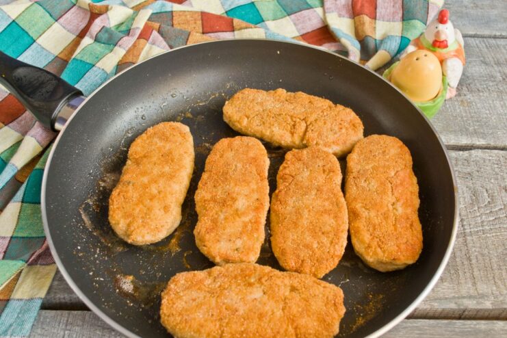 Finishing the chicken cutlets in the oven to ensure they are cooked through A skillet with golden-brown chicken cutlets being placed into an oven.