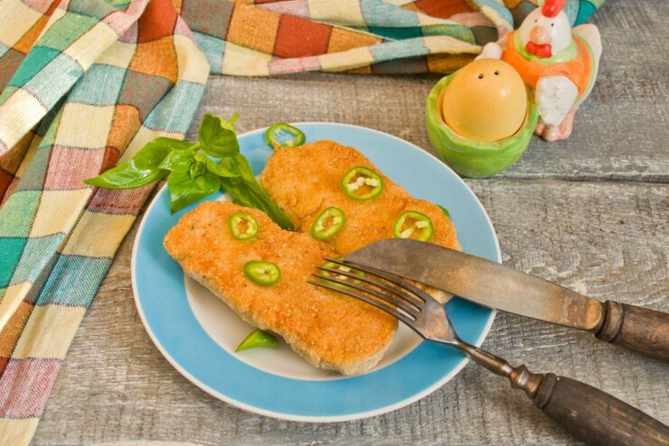 Serving the perfectly cooked chicken cutlets with fresh garnish A plate of cooked, juicy chicken cutlets garnished with fresh herbs and slices of hot pepper.