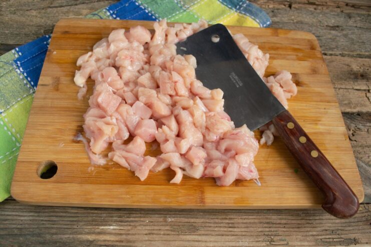 How to Properly Mince Chicken Breast for Cutlets Finely chopped chicken breast on a cutting board, being minced with a knife for cutlets.