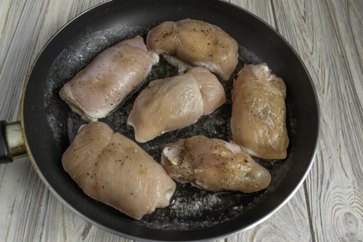 Chicken Cordon Bleu rolls being pan-fried in a skillet until golden brown on all sides.