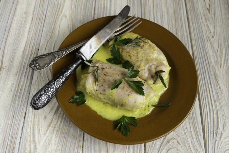A serving of ready-to-eat Chicken Cordon Bleu rolls in béchamel sauce, garnished with herbs.