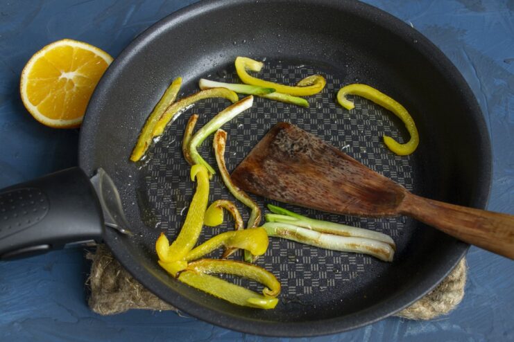 Preparing the filling: Sautéing scallions and bell peppers. Sliced bell peppers and scallions being sautéed in a frying pan.