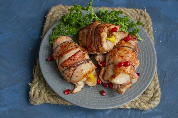 The finished dish: Juicy chicken rolls ready to be served. The finished chicken rolls with bacon in orange sauce on a plate, ready to serve.