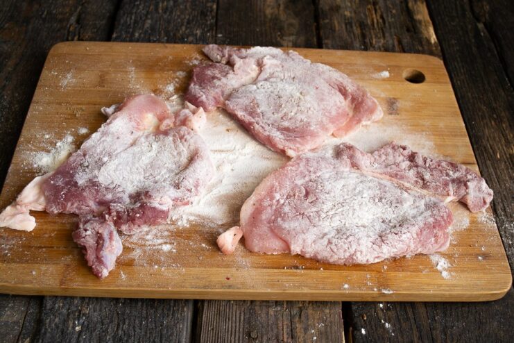 Coating with Flour: The Foundation for a Perfect Breading A pork cutlet fully dredged in flour, ready for the next step of breading.