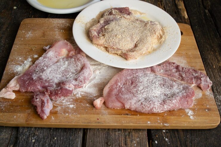 Coating with Breadcrumbs for the Ultimate Crispy Texture Coating an egg-washed pork cutlet evenly with breadcrumbs in a shallow dish.