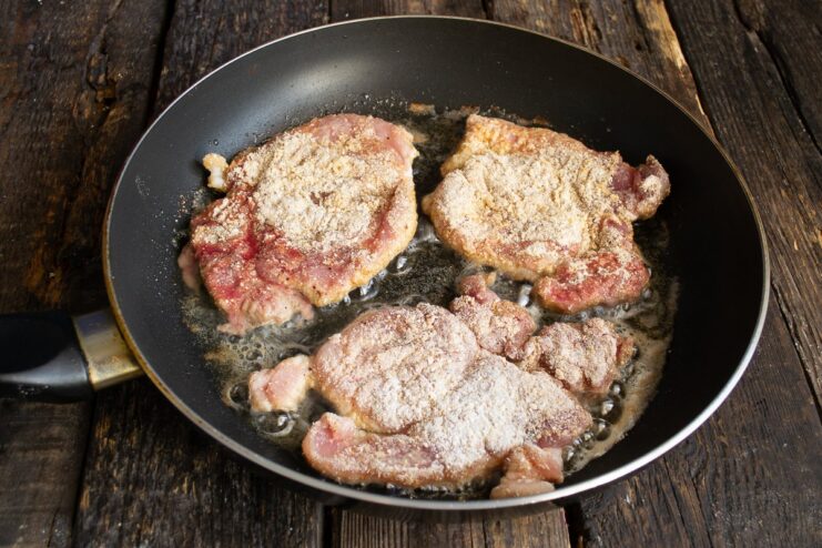 Frying the Schnitzel to a Perfect Golden Brown Pork schnitzels sizzling in a hot pan, frying to a golden brown on one side.
