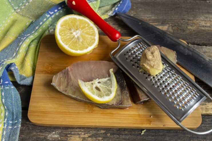 Adding Flavor - Rubbing grated ginger onto the tuna steak. Tuna steaks on a board being rubbed with freshly grated ginger.