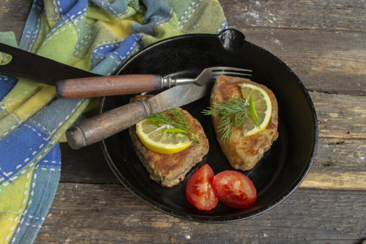 The Finished Dish - Delicious and juicy breaded tuna steak ready to serve. A finished pan-fried breaded tuna steak served on a plate with lemon and herbs.